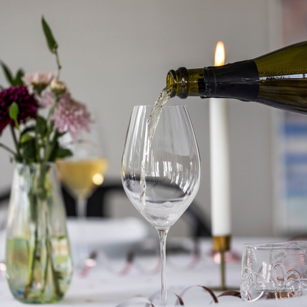 Crement hældes i glas ved festligt opdækket bord med blomster.
