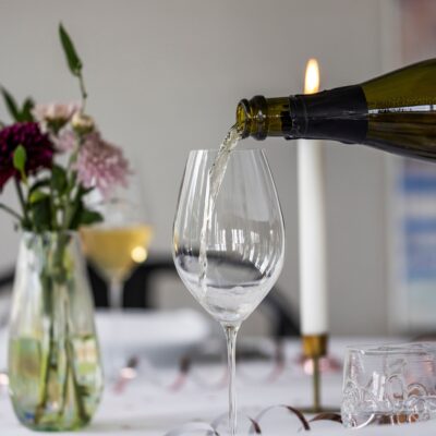 Crement hældes i glas ved festligt opdækket bord med blomster.