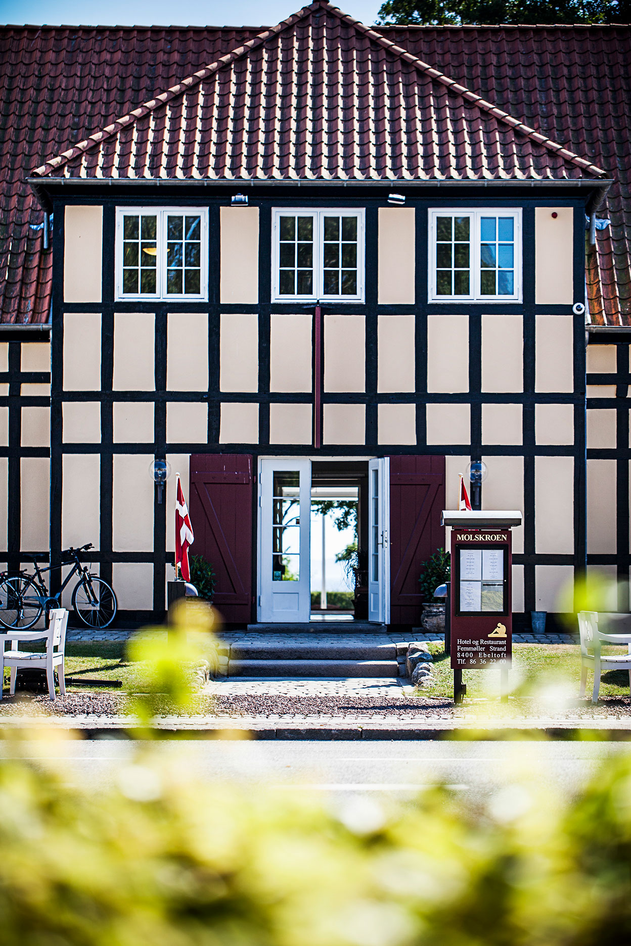 Molskroen facade i bindingsværk med åbne døre og danske flag.