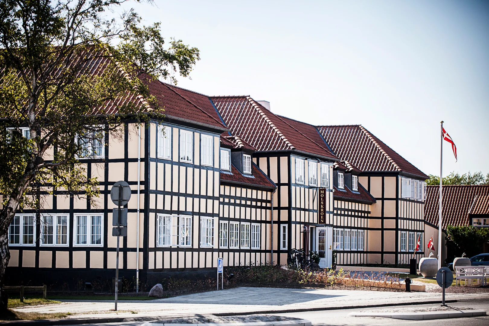 Molskroen facade i bindingsværk med åbne døre og danske flag.