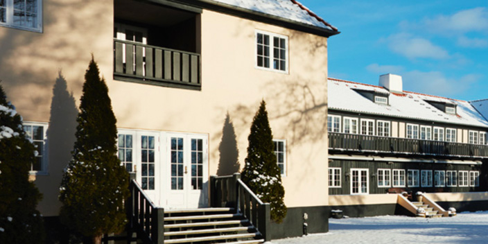 Hotelbygning i vinterlandskab med sne og blå himmel.