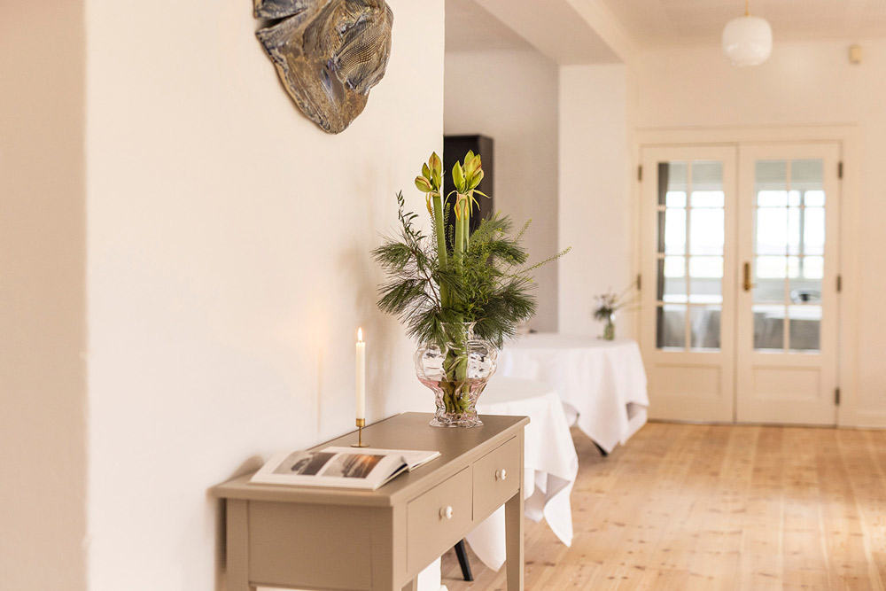 Lyst restaurantlokale med elegante runde borde og kunst på væggen.